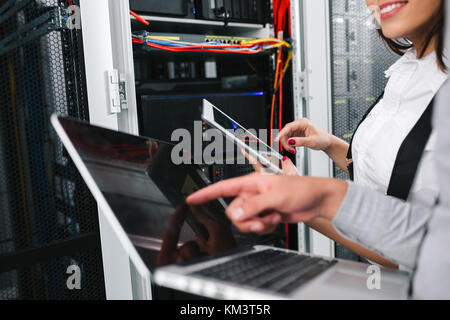 Il team di tecnici che lavorano insieme su server nel centro dati Foto Stock