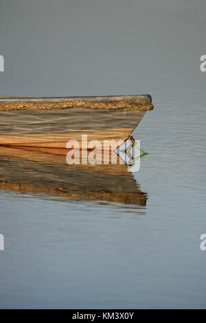 La barca di legno con la riflessione sull'acqua, reed banche in background. Spazio copia superiore e inferiore. Foto Stock