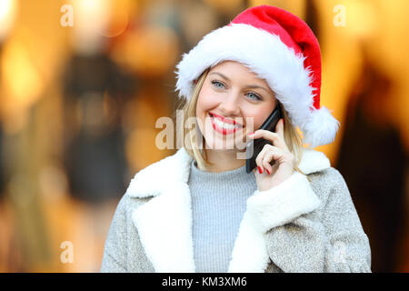 Vista frontale il ritratto di una donna felice chiamando sul cellulare in vacanze di Natale sulla strada Foto Stock