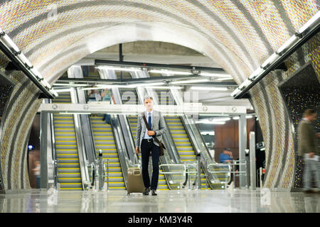 Imprenditore di fronte a scale mobili su una stazione della metropolitana. Foto Stock