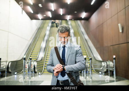 Imprenditore di fronte a scale mobili su una stazione della metropolitana. Foto Stock