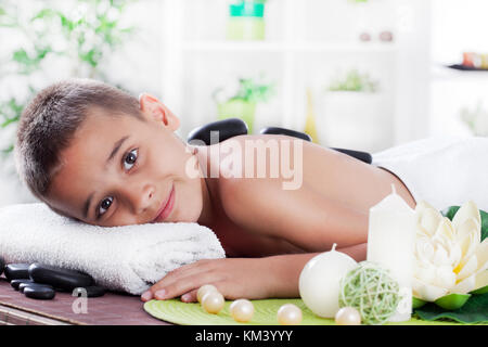 Ragazzo giovane relax nella spa salone con pietra spa Foto Stock