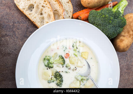 Una grande ciotola bianco casereccio broccoli cremosa ,potato ,formaggio e pancetta minestra con un rustico di crosta di pane e verdure Foto Stock