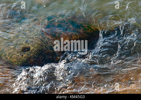 Acqua di mare che lambisce le pietre e ciottoli durante una passeggiata lungo la spiaggia di Old Portsmouth, Regno Unito il 30 novembre 2014. Foto Stock