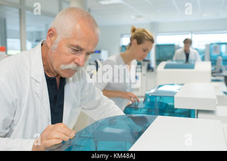 Scienziato anziano utilizzando la macchina su esami di laboratorio Foto Stock