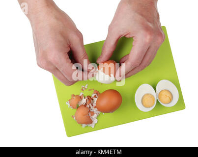 Il vecchio cuoco con le sue mani pulisce l'insalata di uova sode dal guscio. isolata sulla cucina bianca studio shot Foto Stock
