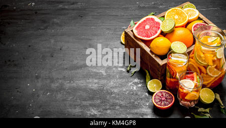 Sfondo di agrumi freschi. succo di agrumi con fettine di lime, arance, pompelmi e limoni. sulla lavagna. Foto Stock