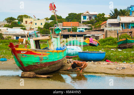 Mui ne, vietnam - 02.11.2017: pescatore pulizia della barca sulla spiaggia al villaggio di pescatori, mui ne, Vietnam Foto Stock