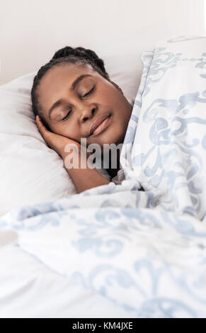 Giovane donna africana che giace nel suo letto Foto Stock