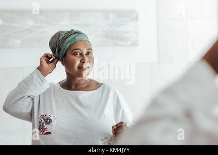 Elegante donna africana messa su un velo nello specchio Foto Stock