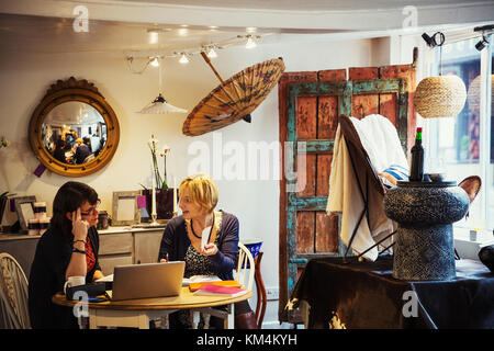 Due donne seduti in un piccolo punto vendita al dettaglio, un popup store, visualizza di retrò e oggetti trovati, riutilizzato e rinnovato. Foto Stock