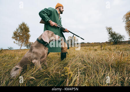 Hunter andando con la pistola e il cane Foto Stock
