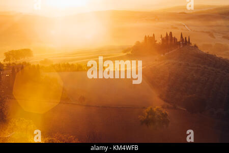 Toscana, paesaggio panoramico con la famosa casa colonica colline e valli in beautiful Golden. La luce del mattino al sorgere del sole in estate, val d'orcia, ital Foto Stock