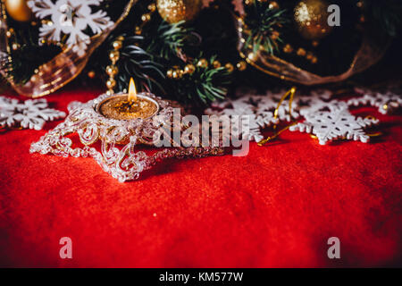 Scheda di natale con abete del ramo decorato con golden baubles, ghirlande e vintage di fiocchi di neve su uno sfondo di colore rosso con una copia dello spazio per il testo Foto Stock