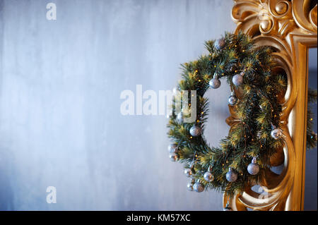 Ghirlanda di Natale con bianco e oro ninnolo decorazioni appeso su una cornice dorata Foto Stock