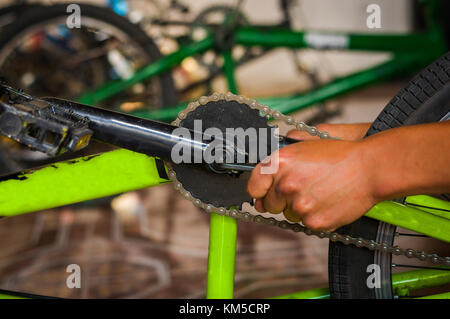 Meccanico di bicicletta regolazione del pedale di bicicletta in un workshop nel processo di riparazione in uno sfondo sfocato Foto Stock