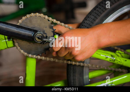 Meccanico di bicicletta regolazione del pedale di bicicletta in un workshop nel processo di riparazione in uno sfondo sfocato Foto Stock