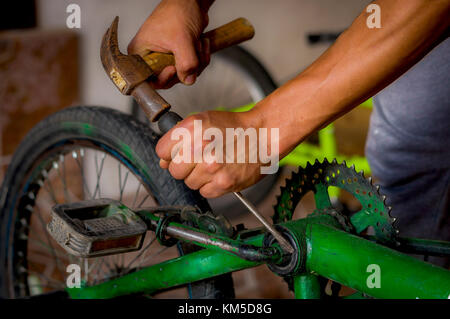 Close up di un uomo che lavora con un martello al di sopra del pedale di bicicletta in un workshop nel processo di riparazione Foto Stock