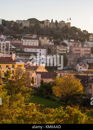 La soa jorge castle a Lisbona, Portogallo, con le case introno architettura, al tramonto. Foto Stock