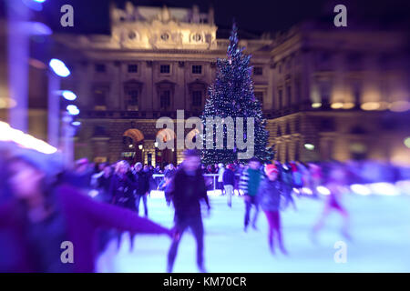 I pattinatori scivolano di notte sulla pista di pattinaggio temporanea di Somerset House a Londra durante il mese di Natale di dicembre Foto Stock