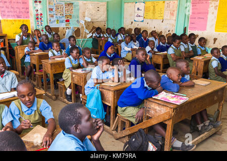 I bambini della scuola secondaria in uniforme si sedevano a banchi di legno ascoltando il loro insegnante durante la lezione, Nairobi, Kenya Foto Stock
