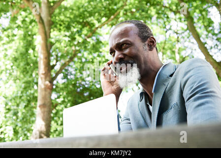 Londra, UK, oltre 50s nero maschio africano chiacchierando al telefono all'aperto, singolo. Foto Stock