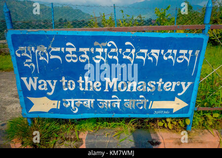 Pokhara, Nepal - 06 ottobre 2017: cartello informativo scritto su di una struttura metallica, indicando con una freccia il modo per monastero Foto Stock