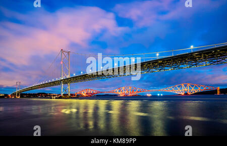 Vista notturna di Forth Road Bridge e Forth Bridge (ferrovia) che attraversa il Firth of Forth a South Queensferry in Scozia, Regno Unito Foto Stock