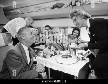 Una vista interna di un aeromobile SAS DC-8 33 degli anni '1960, che mostra la cabina di prima classe e il servizio di bordo tipico dell'epoca. L'immagine cattura l'eleganza e il comfort dei viaggi aerei durante l'età d'oro dell'aviazione. Foto Stock