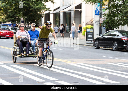 Seattle, Washington, Stati Uniti d'America - 5 settembre 2017: un maschio pedicab sta aumentando la sua mano per dire ciao al trasporto passeggeri nel suo triciclo presso il downtown Foto Stock