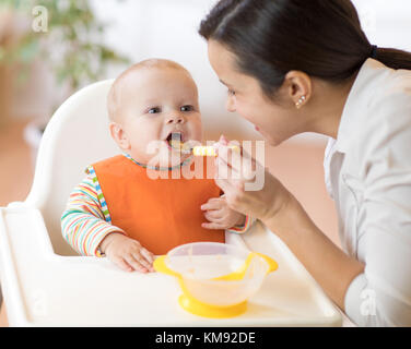 Madre che nutre il suo bambino con cucchiaio. madre dando cibo sano per il suo adorabile bambino a casa Foto Stock