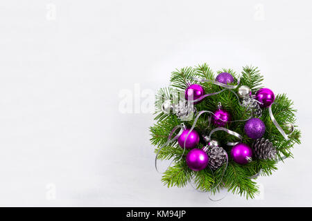 Ghirlanda di Natale con ramo di abete, nastro argentato, pigne, glitter e baubles viola, copia dello spazio. Foto Stock