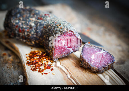 Carne essiccata con pepe e sale in stile rustico sfondo di legno Foto Stock