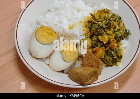 Uovo bollito in Salsa Bruna e arricciatura curry con foglie di betel sul riso Foto Stock