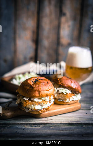 Rustico hamburger di pesce con coleslaw e birra Foto Stock