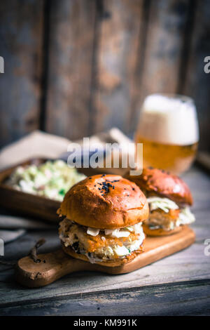 Rustico hamburger di pesce con coleslaw e birra Foto Stock