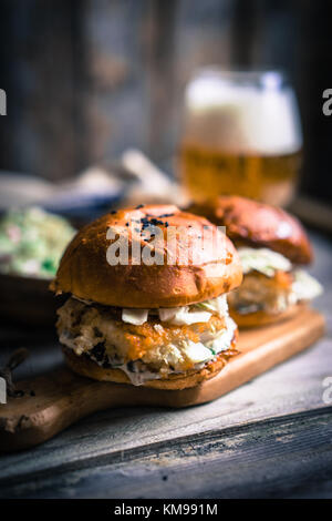 Rustico hamburger di pesce con coleslaw e birra Foto Stock