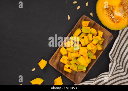 Vegetale di zucca fetta del cubo su pietra nera dello sfondo. Foto Stock