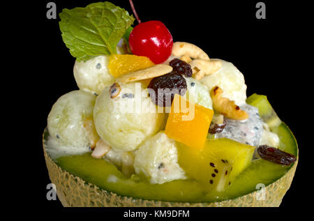 Gelato in melone fresco con insalata di frutta sulla parte superiore isolato su sfondo nero Foto Stock