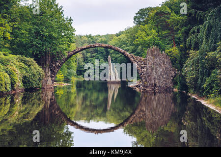 Ponte Rakotz (Rakotzbrucke) noto anche come Ponte del Diavolo in Kromlau, Germania. La riflessione del ponte in acqua crea un cerchio completo. Foto Stock