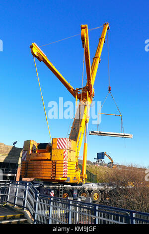 Gigante giallo gru contro il cielo blu lavorando sul ponte ferroviario miglioramenti,Blackpool, Lancashire, Regno Unito Foto Stock