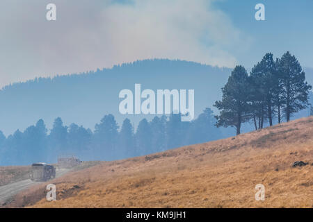 Ranch i veicoli che viaggiano attraverso la fumosa aria da un prescritto masterizzare in Valles Caldera National Preserve, a preservare gestito dal National Park Service Foto Stock