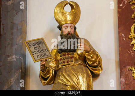 La statua di un santo che tiene un cartello con scritto il testo latino Joannes est nomen Ejus o Giovanni è il suo nome, facendo riferimento a San Giovanni Battista, nella Chiesa Loreta in Foto Stock