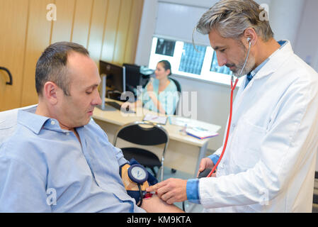 Medico prendendo dell'uomo della pressione del sangue Foto Stock