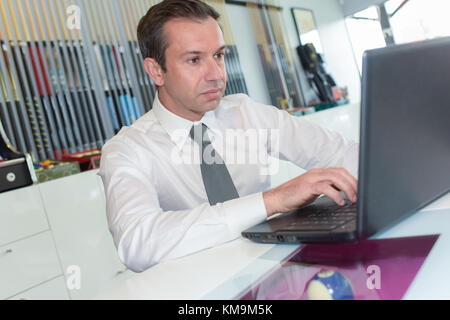 Imprenditore sul portatile in ufficio Foto Stock