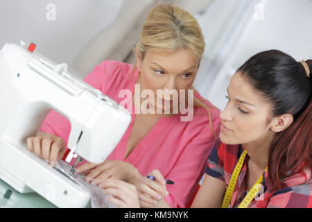 Un gruppo di donne che utilizzano macchine elettriche per cucire in classe Foto Stock