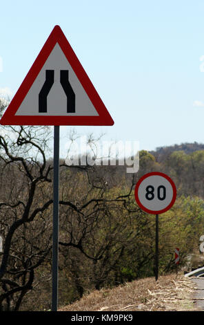 La sicurezza stradale Cartelli, limite di velocità, chevron e la strada si restringe su entrambi i lati davanti Foto Stock