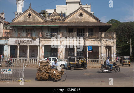 Veicoli in movimento per strada di fronte al vecchio negozio Singer a Mysore, Mysuru, Karnataka, India. Foto Stock