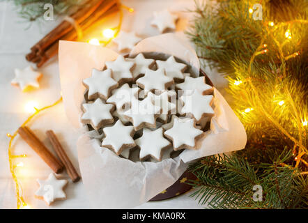 I cookie cannella star in una scatola di latta su uno sfondo di bastoncini di cannella, Abete rami e coni. Foto Stock