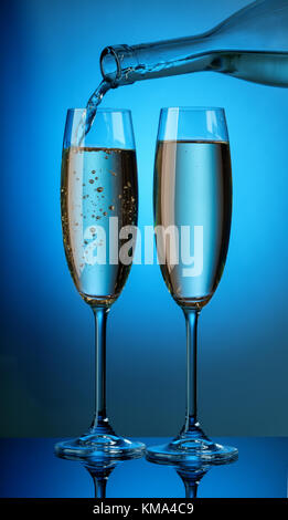 Il champagne aromatico dalla bottiglia è versata in due glasse Foto Stock